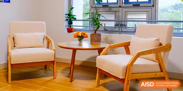A cozy indoor lounge area featuring a wooden coffee table with fresh flowers and a comfortable armchair at Guangzhou ULink International School.