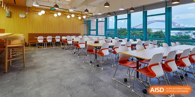 A clean and spacious school cafeteria filled with organized rows of red and white chairs and dining tables at Guangzhou ULink International School.