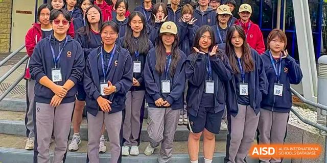 A group of female students in school uniforms smiling and posing together for a group photo on campus at Guangzhou ULink International School.