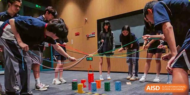 Students participating in a cooperative group activity on a carpeted floor to develop leadership and communication skills at Guangzhou ULink International School.