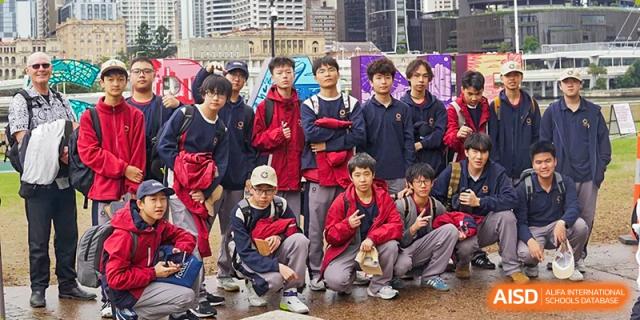 A group of students in navy and red school uniforms posing together outdoors for a group photo at Guangzhou ULink International School.
