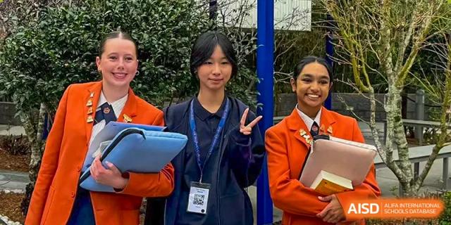 A student smiling while standing outdoors with peers, representing the diverse and friendly student body at Guangzhou ULink International School.