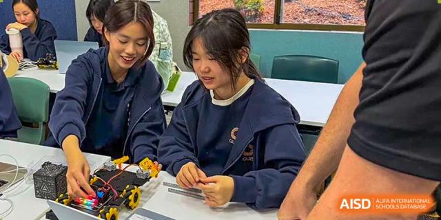 A female student in a navy sweatshirt focuses on a hands-on classroom project at her desk at Guangzhou ULink International School.