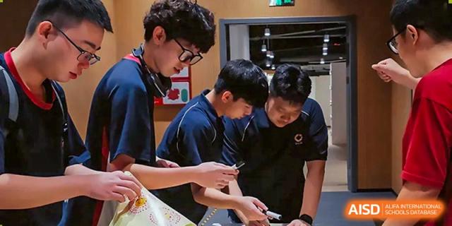 Three male students working closely together on a technical project or STEM activity in a classroom at Guangzhou ULink International School.