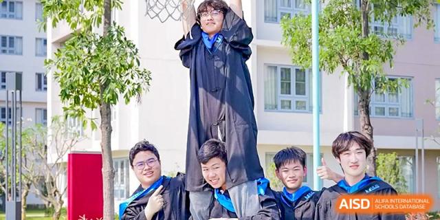 Graduates celebrating their success by posing together in their caps and gowns on the school grounds at Guangzhou ULink International School.