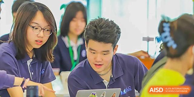 A male student focuses intently on his laptop during an indoor study session or collaborative classroom activity at Guangzhou ULink International School.