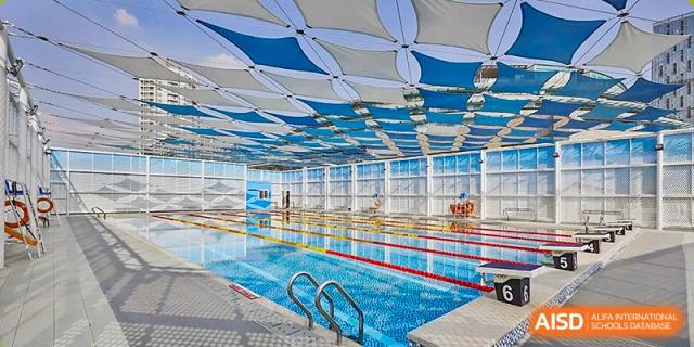 A professional indoor swimming pool with clear blue water and lanes under a unique geometric sunshade roof at Guangzhou ULink International School.