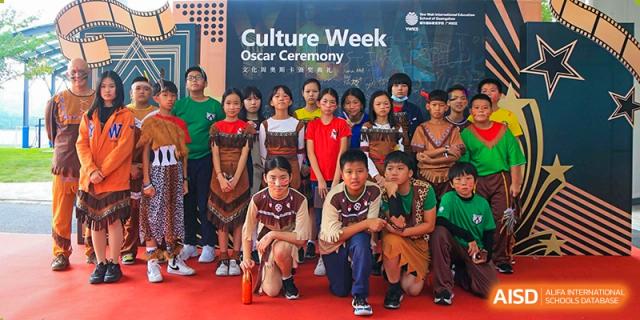 A group of students in traditional patterned vests pose for a Culture Week Oscar Ceremony photo at Yew Wah International Education School of Guangzhou