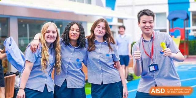 Two female students in striped school shirts smile while walking together outdoors at Yew Wah International Education School of Guangzhou