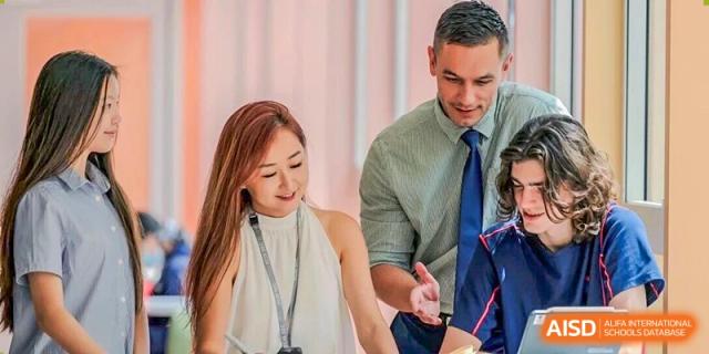 A male and female teacher smile while working together in a brightly lit professional school environment at Yew Wah International Education School of Guangzhou