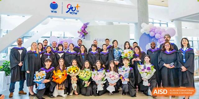 A group of graduates and staff smile while holding large bouquets of flowers during a celebration at Yew Wah International Education School of Guangzhou