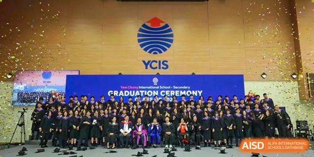 A large group of graduates in academic regalia pose for a formal class photo in front of a YCIS graduation backdrop at Yew Wah International Education School of Guangzhou