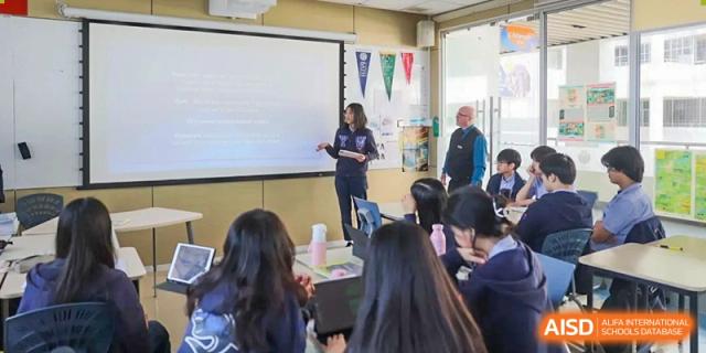 A female teacher gives a presentation to a group of students sitting at desks in a brightly lit classroom at Yew Wah International Education School of Guangzhou