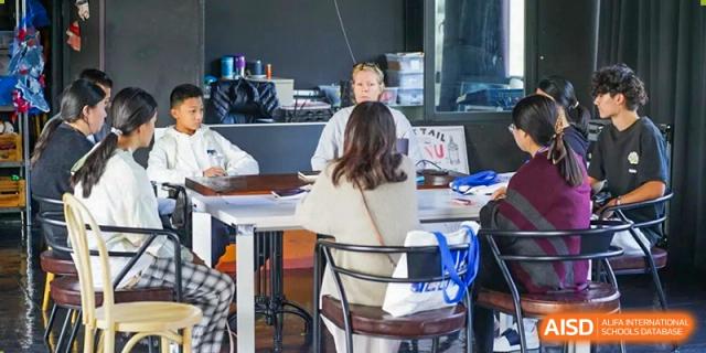 A teacher speaks with a student at a desk in a modern classroom during an individualized learning session at Yew Wah International Education School of Guangzhou