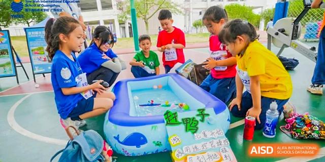 Young children gather around a small blue inflatable pool for a water-based activity during a school event at Yew Wah International Education School of Guangzhou