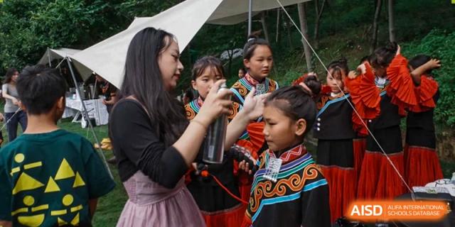 A woman helps prepare students in traditional embroidered clothing for a cultural performance at Yew Wah International Education School of Guangzhou
