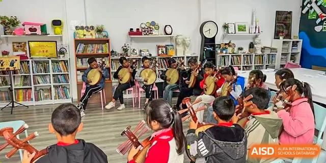 A classroom of students sit in a circle while practicing traditional stringed instruments together at Yew Wah International Education School of Guangzhou