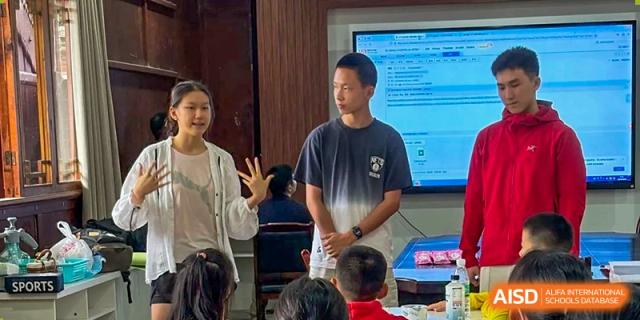 Two educators lead a collaborative classroom discussion with students, utilizing a large digital screen for a modern interactive learning session at Beanstalk International Bilingual School Shunyi Campus.