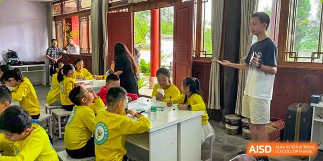 A group of students work together at white tables in a traditional architectural setting, engaging in collaborative peer-to-peer learning at Beanstalk International Bilingual School Shunyi Campus.