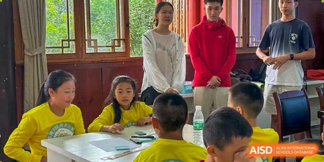 An instructor in a white shirt guides a small group of students through a hands-on activity in a classroom with large windows at Beanstalk International Bilingual School Shunyi Campus.
