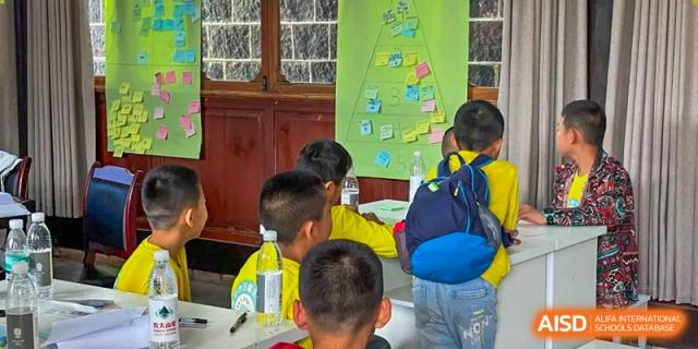 Students in yellow long-sleeved shirts participate in a group workshop, using sticky notes and creative boards to organize their thoughts at Beanstalk International Bilingual School Shunyi Campus.