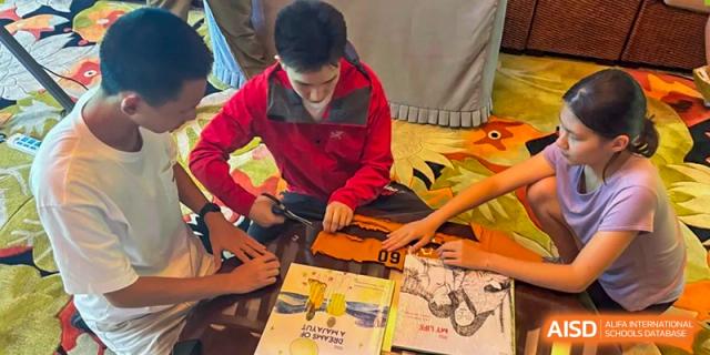 A teacher in a red jacket demonstrates a technical skill to a student, providing one-on-one mentorship during a specialized workshop at Beanstalk International Bilingual School Shunyi Campus.