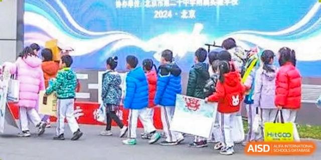 Young students in colorful winter jackets line up outdoors for a school activity, holding onto a banner during a crisp morning at Beanstalk International Bilingual School Shunyi Campus.