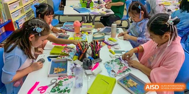 Students sit at a table covered in colorful art supplies, focusing on a creative craft project during an engaging afternoon workshop at Beanstalk International Bilingual School Shunyi Campus.