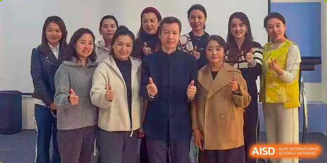 A group of professional staff members in formal and business-casual attire pose together for a team photo in a brightly lit school hallway at Beanstalk International Bilingual School Shunyi Campus.
