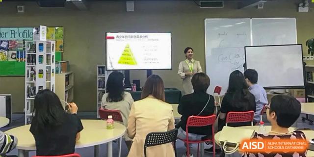 A teacher leads an interactive lecture for a group of attentive staff members, using a whiteboard and digital display to share ideas at Beanstalk International Bilingual School Shunyi Campus.