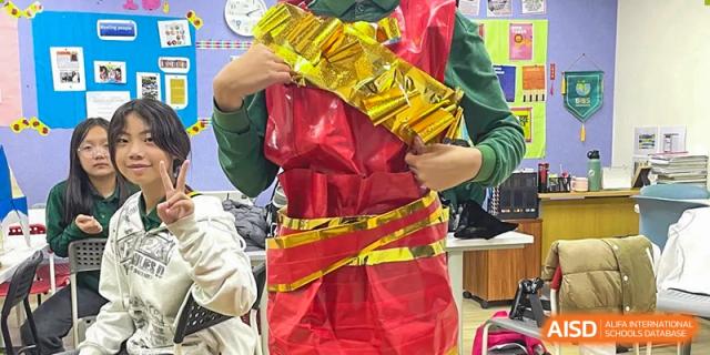 A student wears a creative and bulky costume made of shiny red and gold materials, participating in a fun recycled fashion project or drama activity at Beanstalk International Bilingual School Shunyi Campus.