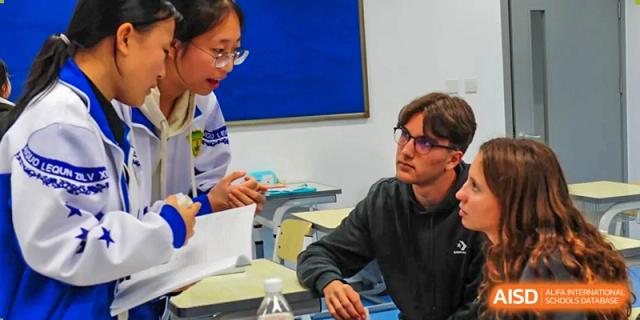 A group of diverse students gathers around a desk to collaborate on a project and share ideas during an interactive seminar at Beijing LuHe International Academy.