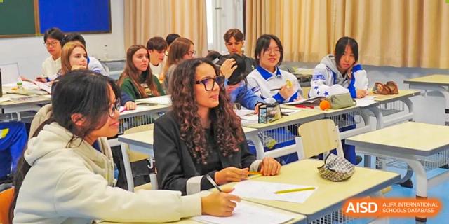 Students with various backgrounds sit at their desks and engage in a thoughtful group discussion during a dynamic and inclusive seminar session at Beijing LuHe International Academy.