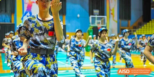 Students in camouflage uniforms focus intently while practicing hand-to-hand combat drills and defensive postures during their annual military training at Beijing LuHe International Academy.