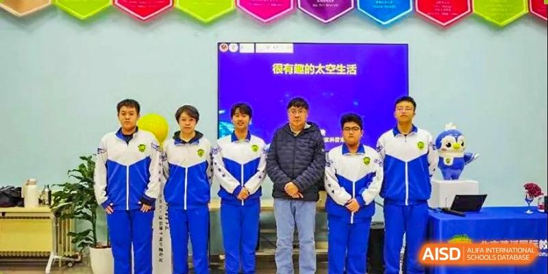 Six students in matching blue and white tracksuits stand in a line against a blue presentation screen during an academic assembly or competition at Beijing LuHe International Academy.