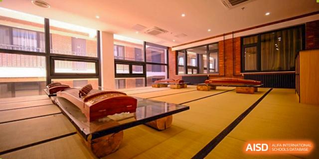 A traditional Chinese classroom features wooden musical instruments called guzheng arranged on low tables atop tatami mats, creating a serene space at Beijing Tongzhou Shuren Private School.
