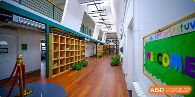 A wide, modern hallway features polished wooden floors and extensive built-in shelving, reflecting the clean and organized architectural design of Beijing Tongzhou Shuren Private School.