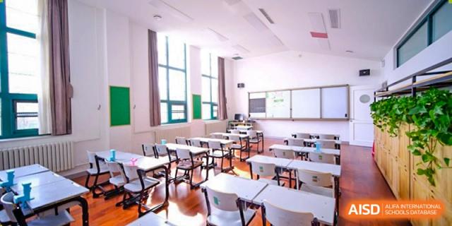 This well-lit classroom features wooden desks and a large green chalkboard, providing a comfortable and focused environment for student academic growth at Beijing Tongzhou Shuren Private School.