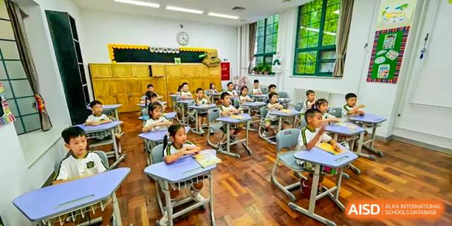 Primary school students are seated in a bright, modern classroom, following along with their teacher during a structured and engaging academic lesson at Beijing Tongzhou Shuren Private School.