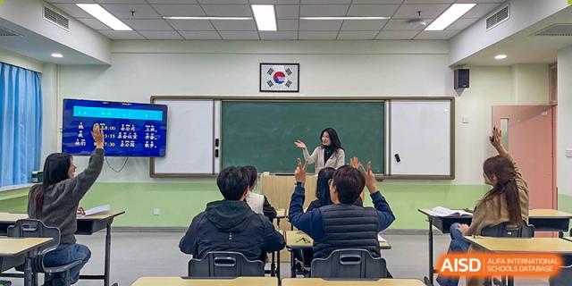 Young students sitting at their desks hold up colorful educational pamphlets to show their progress during a dedicated lesson at the Korean International School In Beijing.