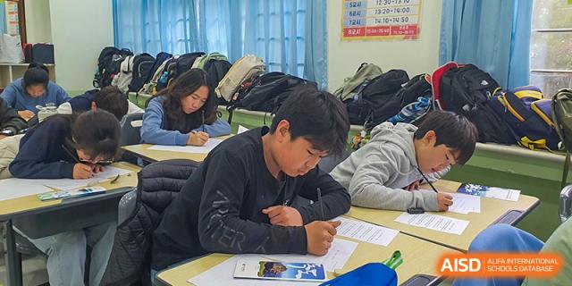 Several students are captured from a side angle as they concentrate on completing their paper-based assignments during a study session at the Korean International School In Beijing.
