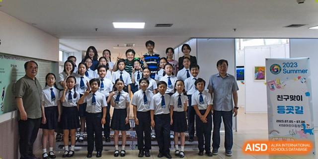 A large group of students in formal white and navy uniforms stand neatly in rows with their teachers for a formal portrait inside the Korean International School In Beijing.