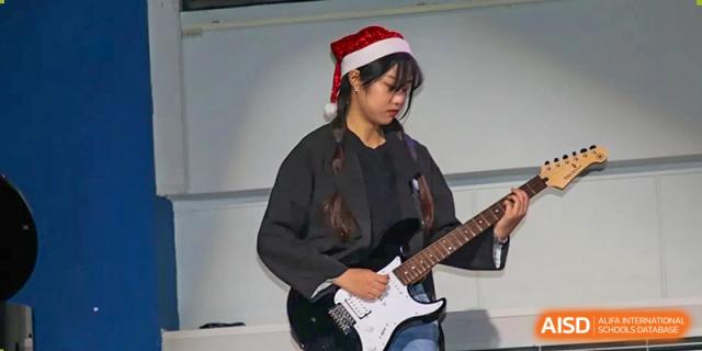 A student wearing a Santa hat plays an electric guitar during a holiday-themed concert at Korean International School In Beijing.