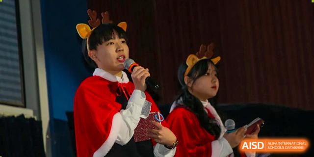 Two students wearing reindeer antlers speak into microphones during a festive school event at Korean International School In Beijing.