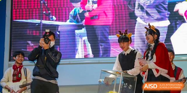 A student wearing reindeer antlers picks a name from a box during a raffle or prize draw at Korean International School In Beijing.