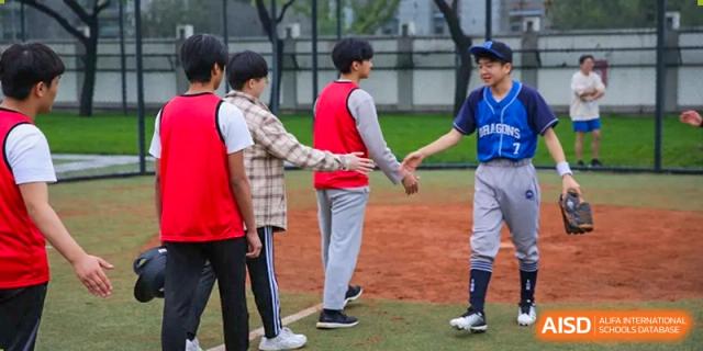 Baseball players in red and blue jerseys shake hands at home plate after a competitive game at Korean International School In Beijing.