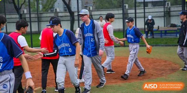 Opposing baseball team members in blue "Dragons" jerseys walk past each other during a post-game handshake at Korean International School In Beijing.