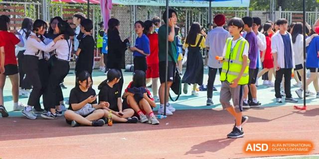 Female students wearing blue numbered jerseys stand in a line with their ankles tied together for a three-legged race challenge during a sports day at the Korean International School In Beijing.