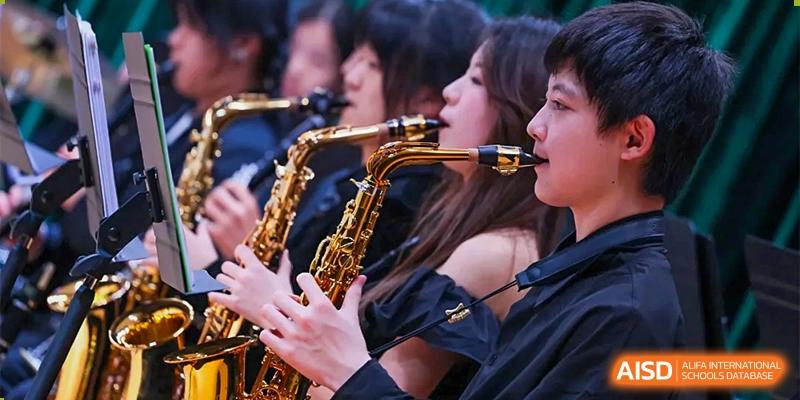 A group of students in formal black attire perform together as part of a saxophone section in the school orchestra at Beijing World Youth Academy.