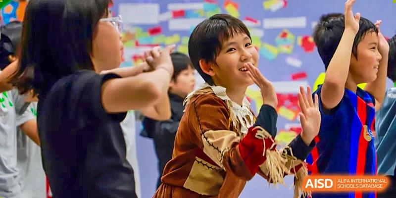 A young student in a feathered costume smiles and performs during a creative arts or drama production on stage at Beijing World Youth Academy.